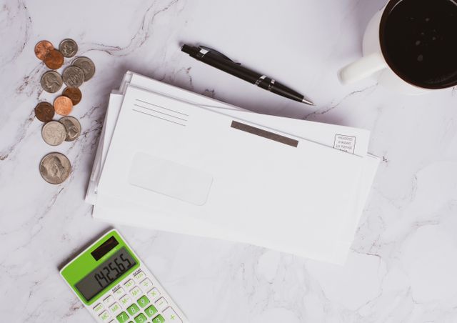a stack of envelopes next to a calculator and coins